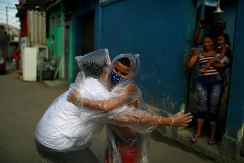 La maestra Maura Silva, que trabaja para la escuela pública Escola Municipal Frei Vicente de Salvador y que creó un 'kit de abrazo' con fundas de plástico, abraza a su alumno Yuri Araujo Silva en el barrio pobre de Padre Miguel, en Río de Janeiro.