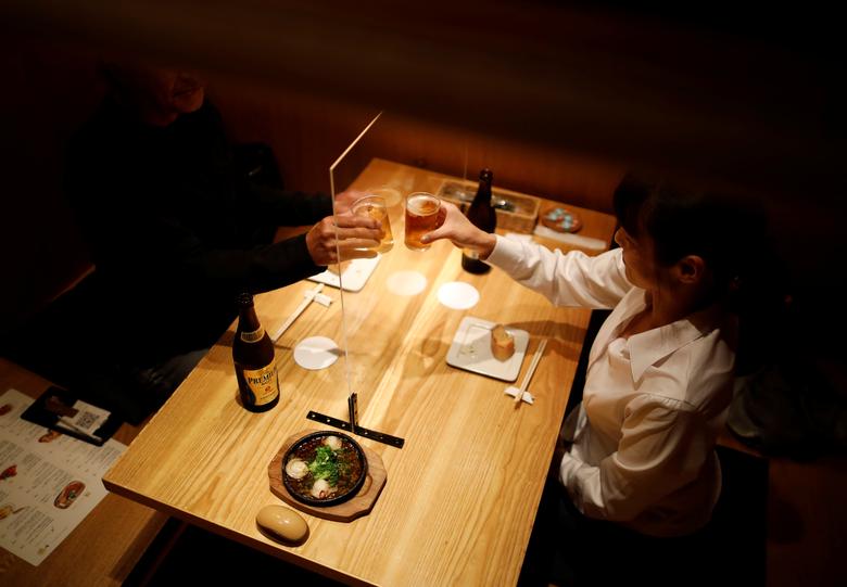 Los clientes brindan con cerveza detrás de un tablero de plástico transparente en Kichiri Shinjuku, en Tokio.