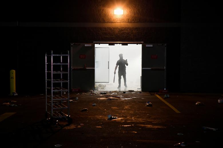 Se ve a un manifestante entre el humo en el supermercado Cub saqueado cerca del tercer recinto de la policía de Minneapolis.