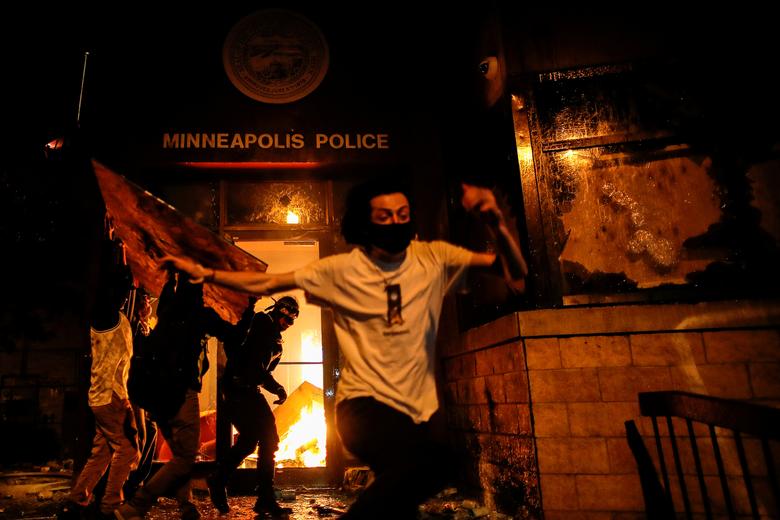 Los manifestantes reaccionan cuando prendieron fuego a la entrada de una estación de policía mientras continúan las manifestaciones.