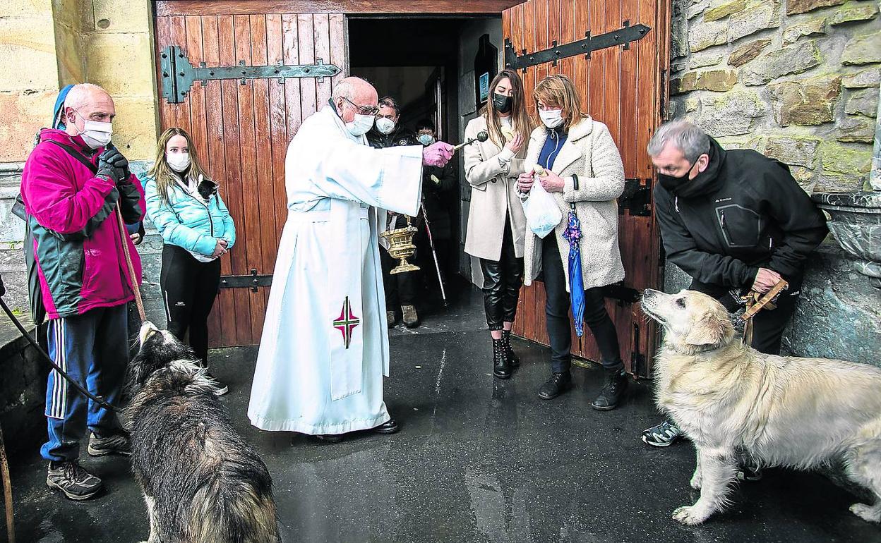 El sacerdote Antonio Madinabeitia bendice a dos perros a las puertas del santuario. 