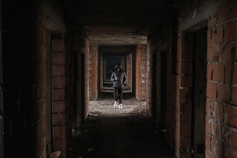 Un migrante camina hacia un edificio abandonado donde está en cuclillas