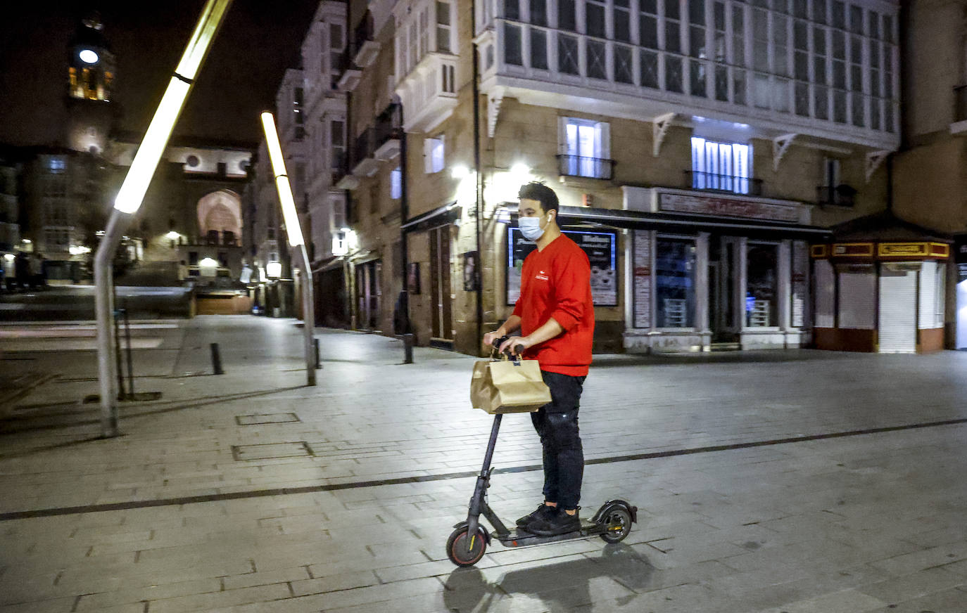 Un trabajador de reparto a domicilio circula por la calle Postas en patinete.