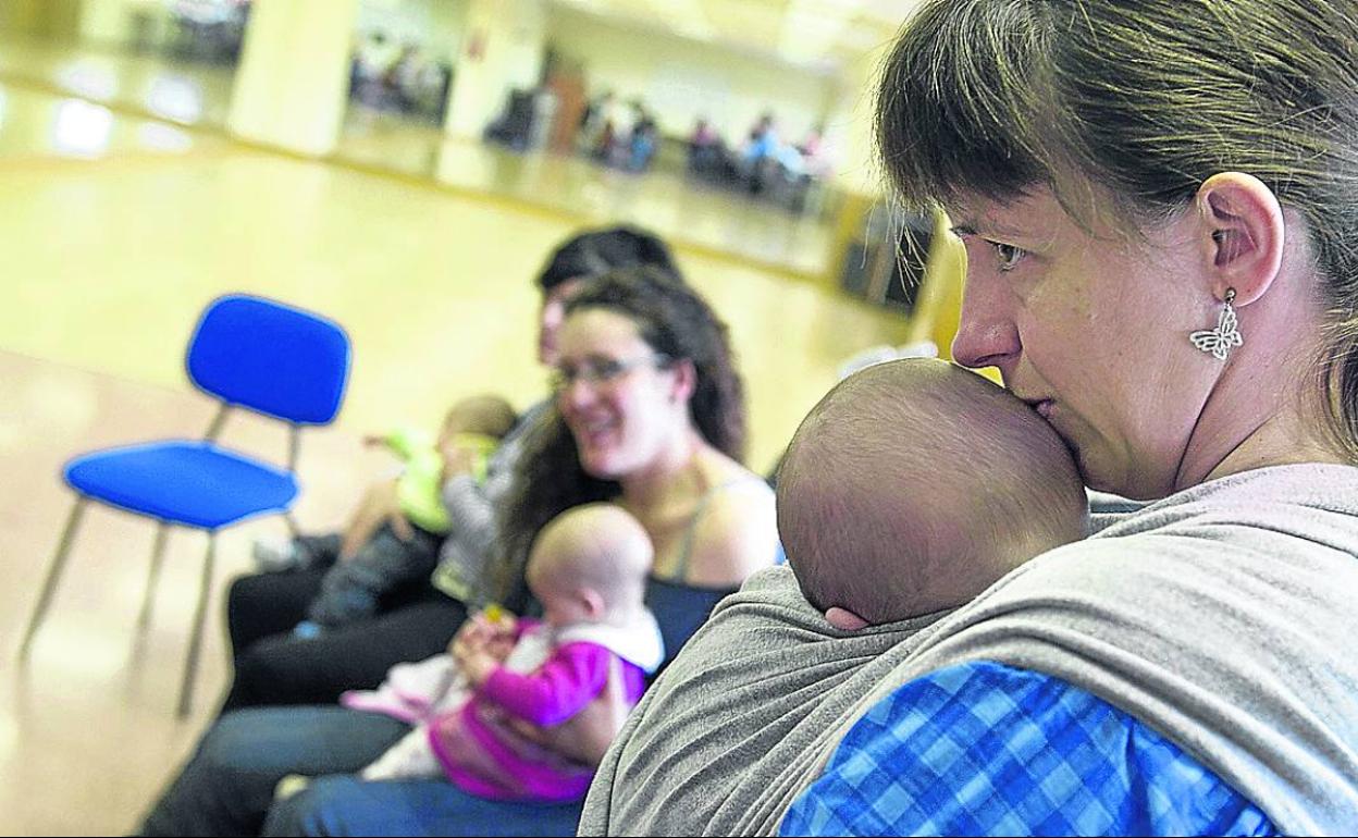 Una madre atiende a su bebé de meses en una actividad de un grupo de lactantes. 