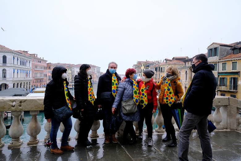 Los turistas usan corbatas de colores en el puente de Rialto para celebrar el carnaval anual de Venecia, que ha sido cancelado este año debido al coronavirus en Venecia.