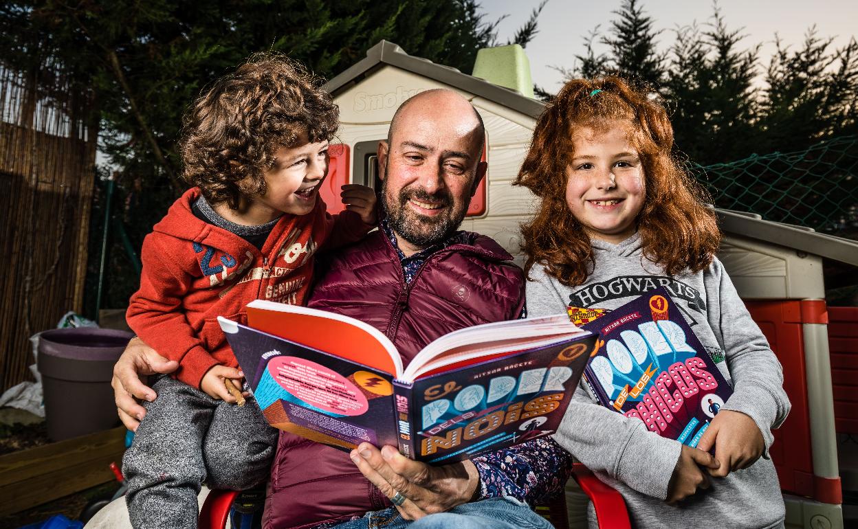 Ritxar Bacete, con sus dos hijos mayores, hojea uno de sus libros.