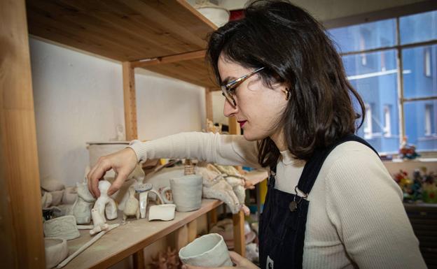 La artista ordena varias piezas pequeñas de cerámica en su estudio.