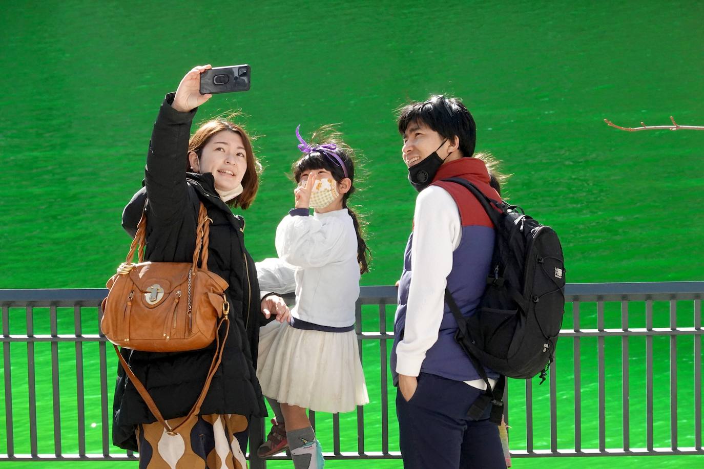 Turistas se hacen fotos en el río Chicago después de haber sido teñido de verde en celebración del Día de San Patricio en Chicago, Illinois.