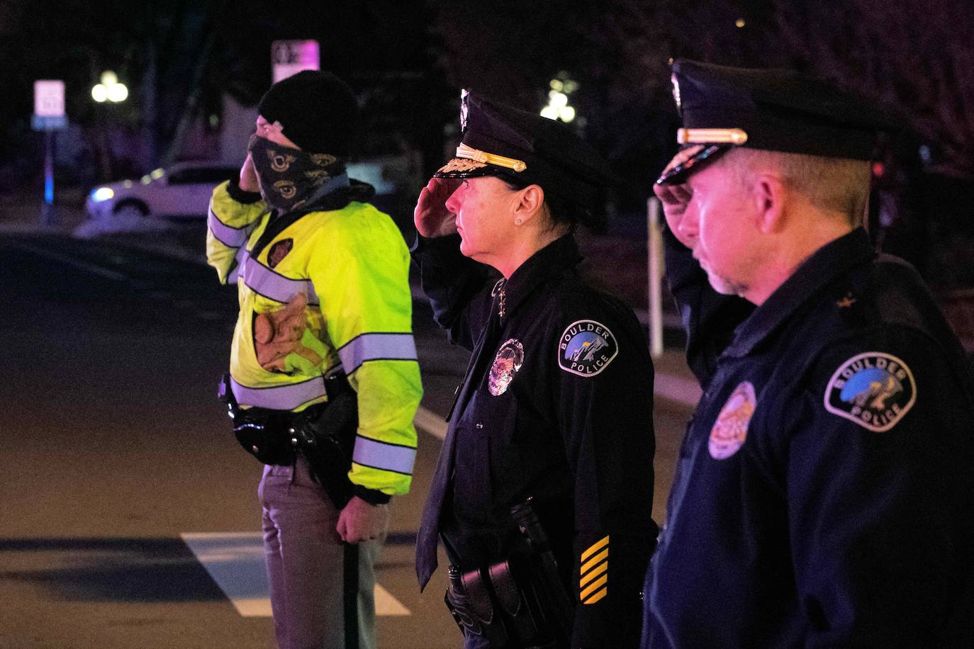 El personal de las fuerzas del orden público saluda cuando la caravana que transporta al oficial de policía de Boulder caído Eric Talley sale de la tienda de comestibles King Soopers en Boulder