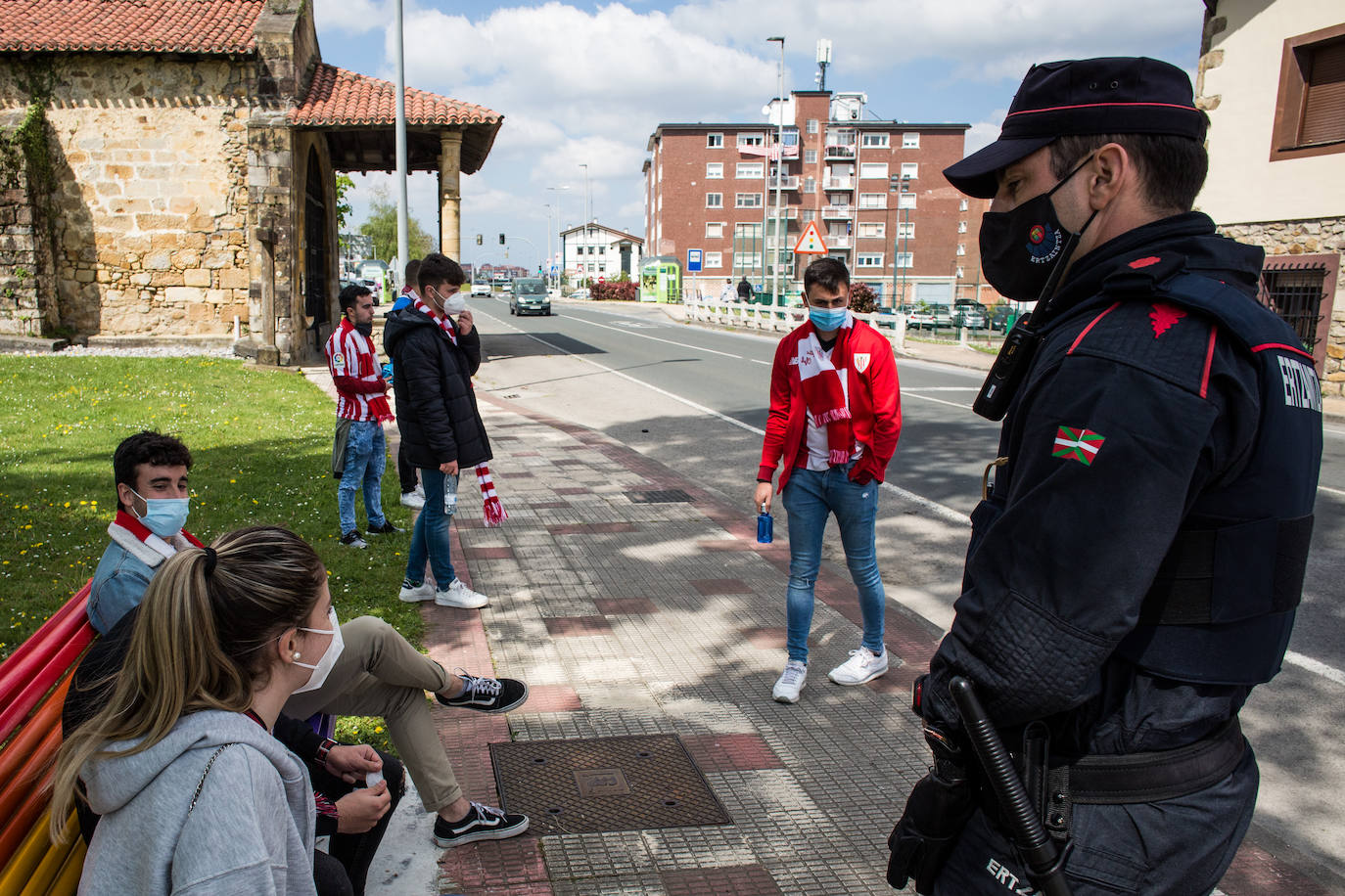 Un ertzaina charla con un pequeño grupo de aficionados en los alrededores de Lezama.