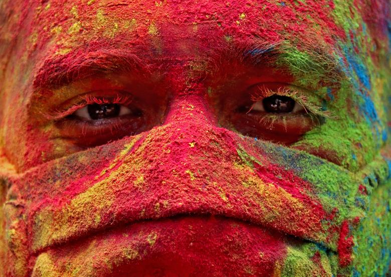 Un hombre que llevaba una máscara protectora embadurnada mira durante las celebraciones de Holi en Mumbai, India.