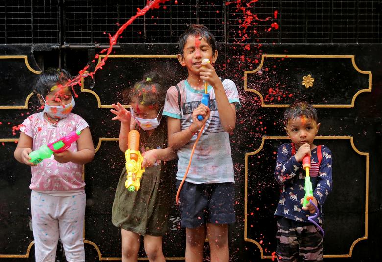 Los niños reaccionan cuando son salpicados con agua coloreada durante las celebraciones de Holi en Chennai, India.