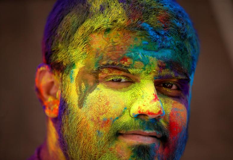 Un hombre pintado de colores observa durante las celebraciones de Holi en Ahmedabad, India.