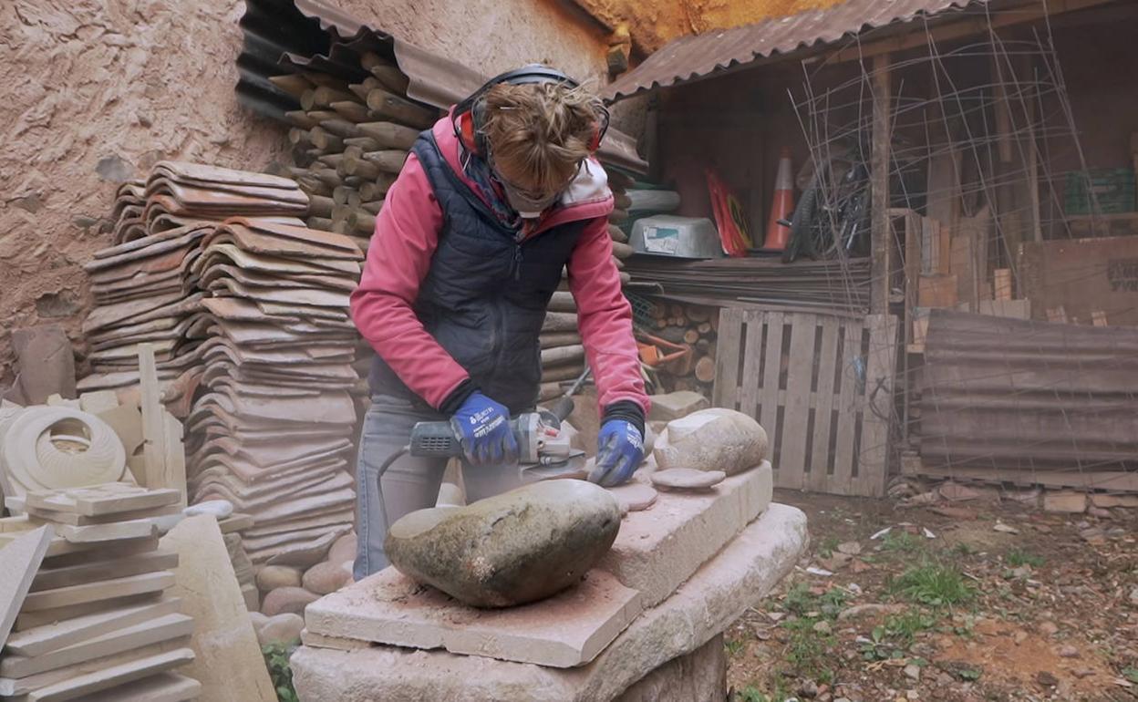 Adriana trabaja en la creación de una de sus esculturas, trabajando firme sobre la piedra. 