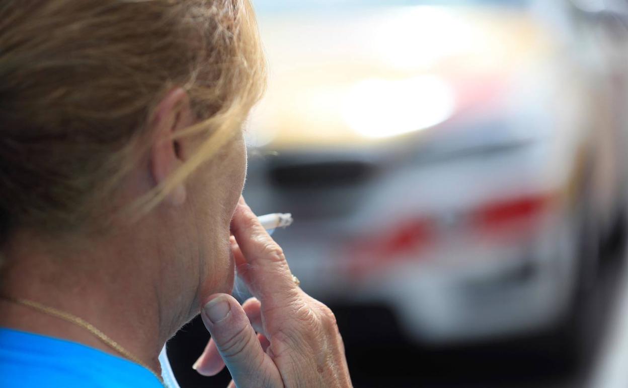 Una mujer fuma en la calle.