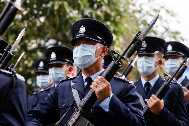 La policía usa máscaras faciales mientras realiza el ejercicio de pie de "paso de ganso" durante una jornada de puertas abiertas para conmemorar el Día de la Educación en Seguridad Nacional, en la Escuela de Policía de Hong Kong.