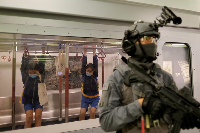 Los niños juegan detrás de un miembro del equipo de respuesta ferroviaria en un modelo de una estación de ferrocarril de tránsito masivo (MTR).