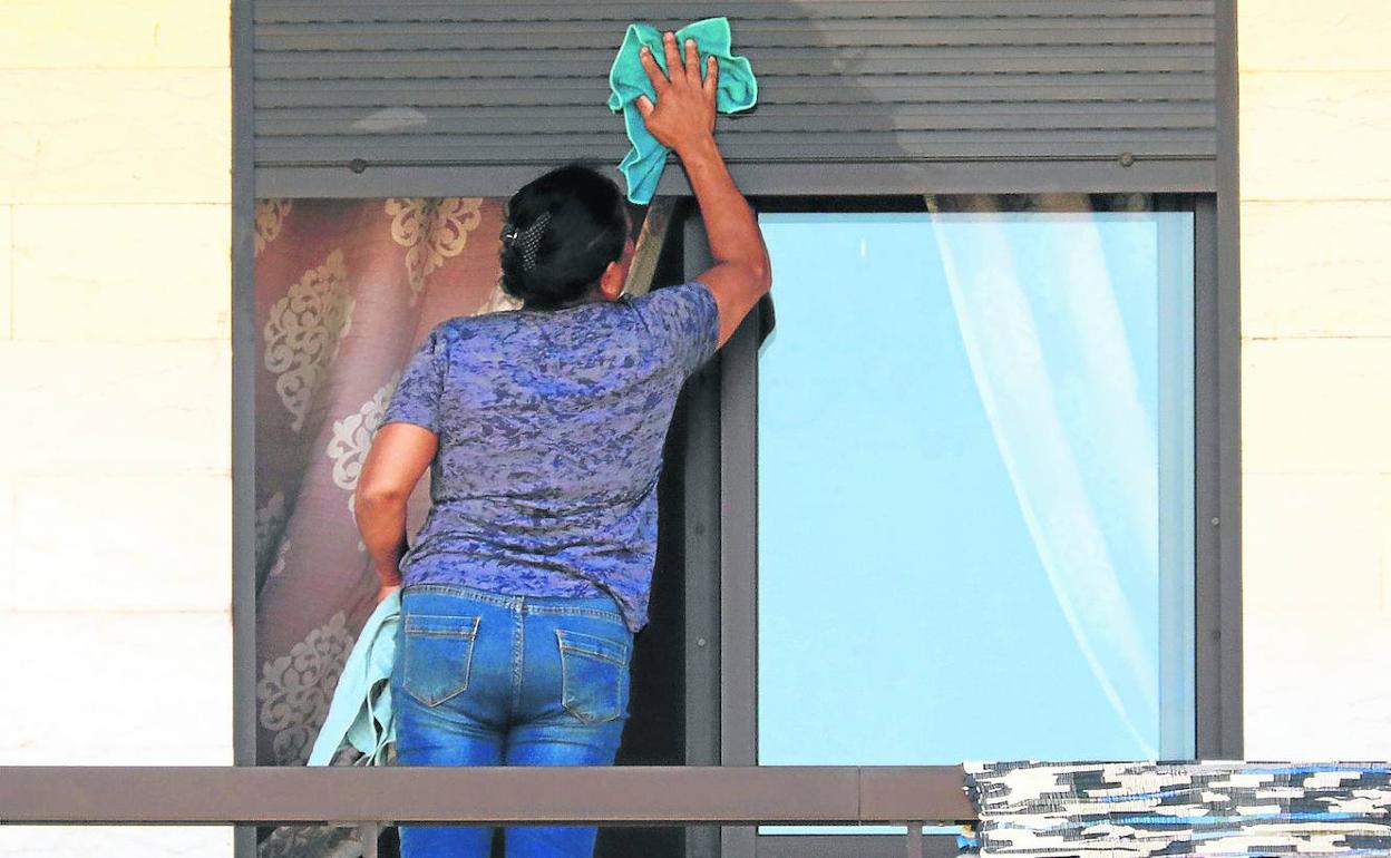 Una empleada del hogar limpia las ventanas de la casa en la que trabaja. 