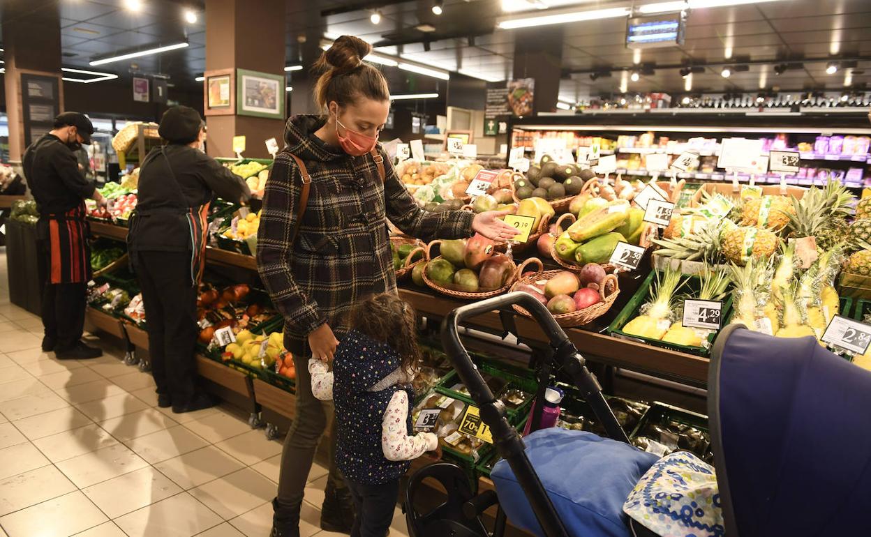 Una familia en la zona de frutería en una tienda en Bilbao recién renovada'. 