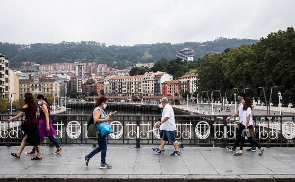 Gente paseando por el Puente del Arenal de Bilbao , con mascarillas.