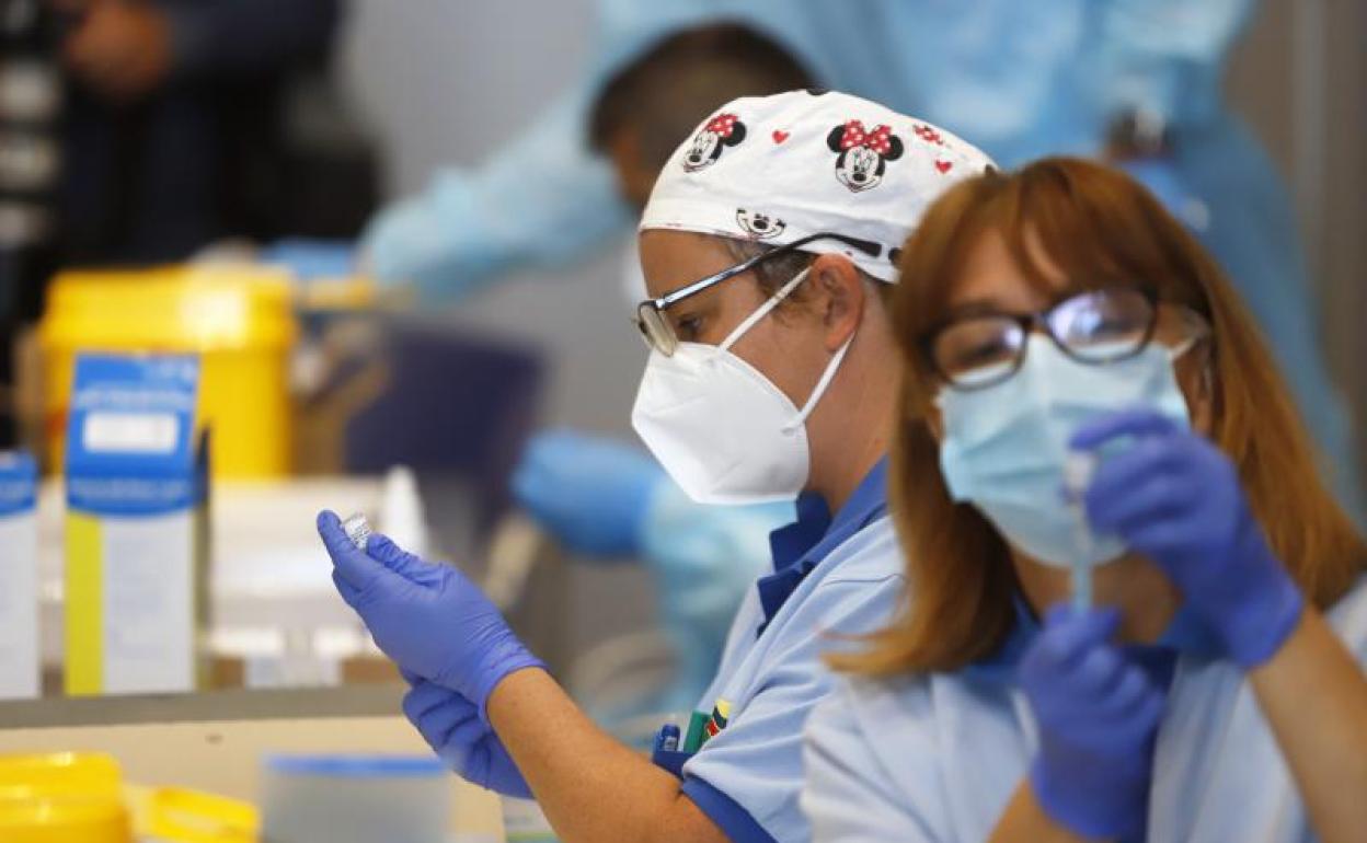 Dos sanitarias preparan varias dosis de vacunas. 