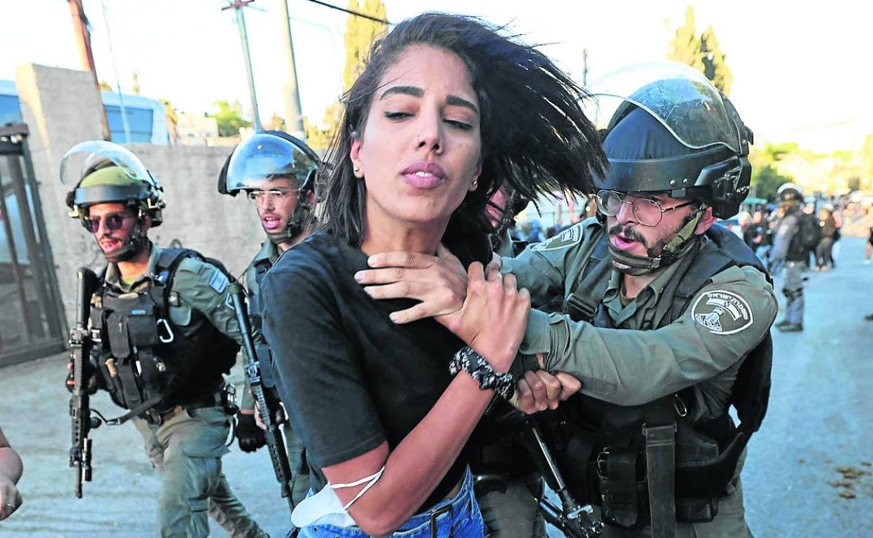 Fuerzas israelíes se disponen a detener a una joven palestina en el barrio de Sheikh Jarrah, en Jerusalén.