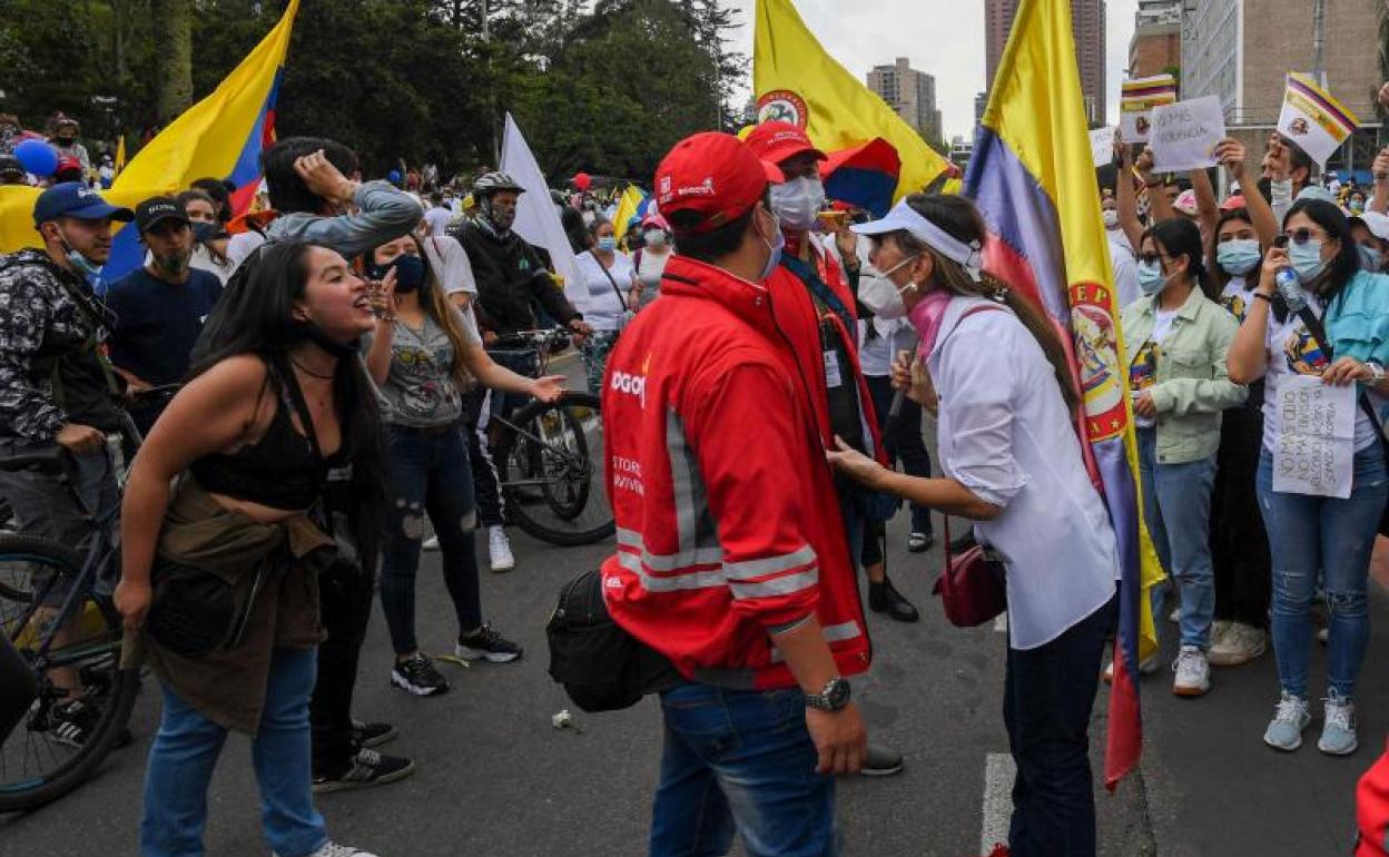 Una mujer contraria a las huelgas y manifestaciones se enfrenta a una de las participantes en una protesta en Bogotá.