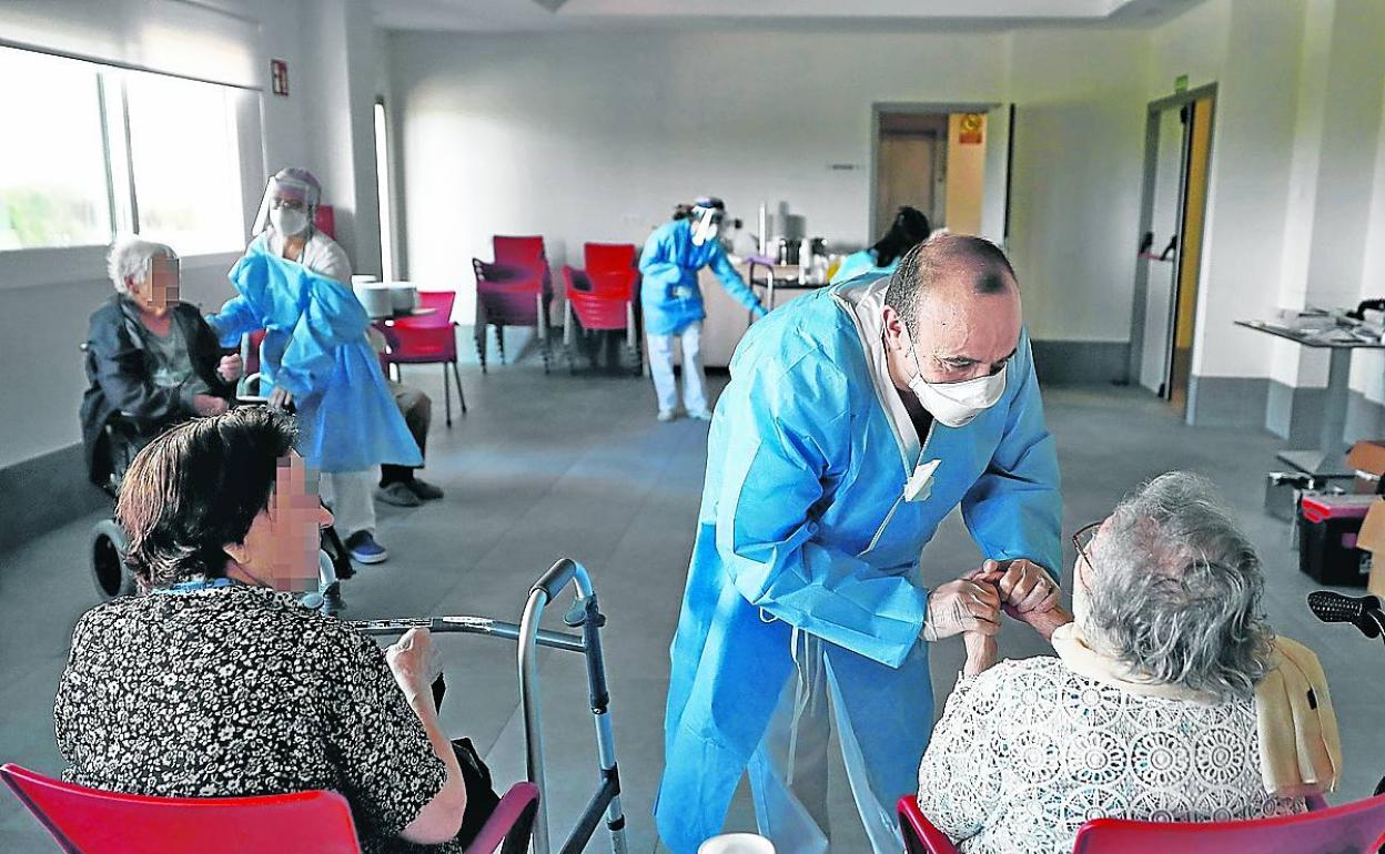 Un gerocultor charla y coge las manos de una mujer dependiente en una residencia. 