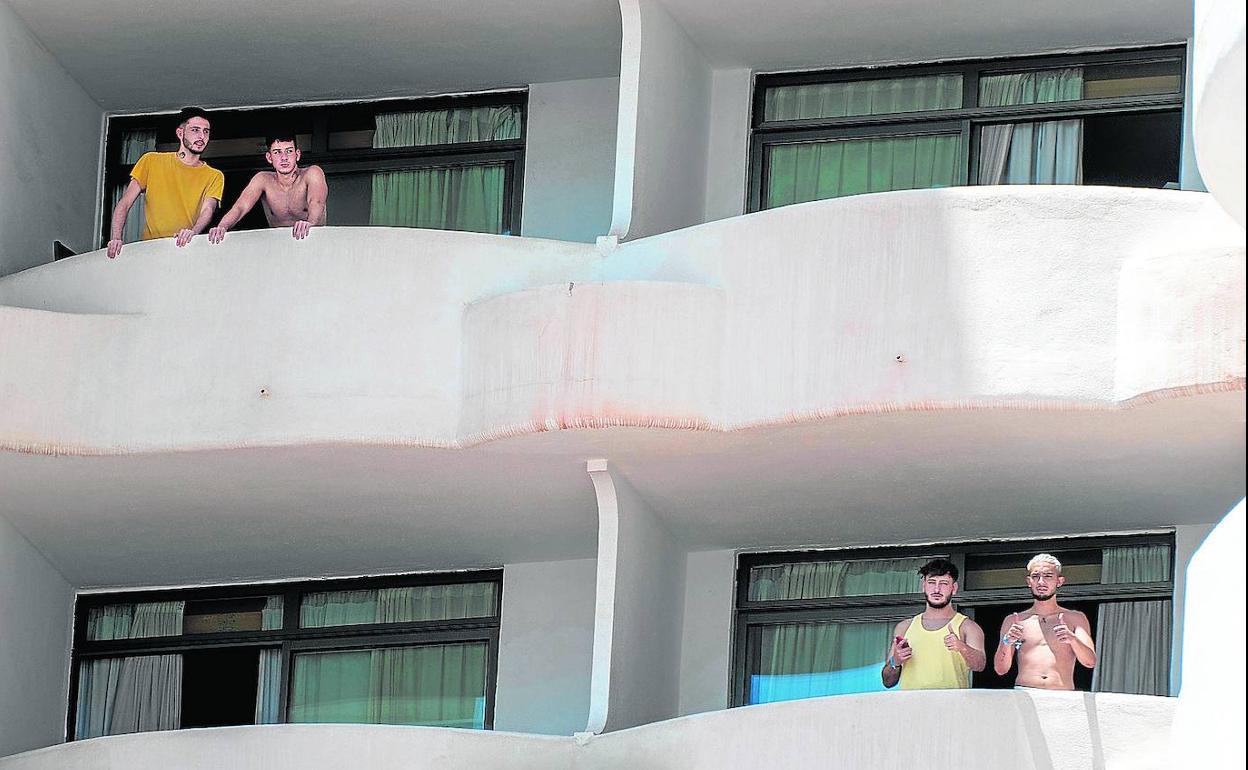 Varios jóvenes se asoman a los balcones del hotel Palma Bellver en el que permanecen confinados bajo vigilancia policial. 