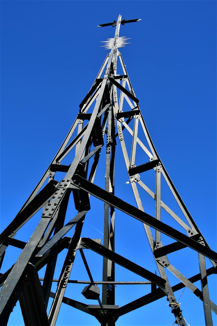 La Cruz . El símbolo de Gorbeia no es, etnográficamente hablando, el vestigio humano más importante de Gorbeia. Pero sí el más popular. Fue erigida en 1901 para cumplir la orden del papa León XIII de levantar cruces en la cumbres más altas de la cristiandad para conmemorar la entrada del nuevo siglo. Las dos primeras que se levantaron medían 33 metros de altura (la edad de Jesucristo cuando fue crucificado) pero sucumbieron a las inclemencias meteorológicas y apenas duraron unos meses en pie. La actual, de la que no se conoce la fecha exacta en que fue plantada (las primeras noticias de ella son de 2012), mide 17 metros, es una copia de la Torre Eiffel y reparte los cuatro pilares sobre los que se sustenta entre Bizkaia y Álava.