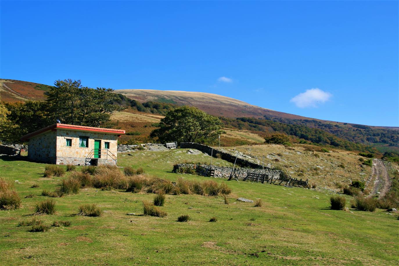 Txabola de Gorrostiano . El gran número de bordas pastoriles construidas confirma la relevancia que tuvo el pastoreo en el macizo del Gorbeia. Los pastores vivían de mayo a noviembre en ellas, donde trabajaban cuidando el ganado y elaborando queso de manera artesanal. Los pastores solicitaban autorización al municipio o al dueño del terreno para construir su vivienda a cambio de una módica cantidad, pero no adquirían ningún derecho de propiedad. Además, si un pastor no regresaba a su chabola la temporada siguiente, otro podía ocuparla. Eran pequeñas construcciones orientadas al este y ubicadas en lugares protegidos del viento. Las paredes de mampostería seca realizada con cantos de caliza tenían poco más de un metro de altura y el tejado estaba hecho con tepes de tierra cubiertos de césped. La de Gorrostiano, en la alavesa ruta hacia la cruz desde Arlobi, y punto de inicio de la mágica Senda Basatxi, fue una de las más populares. La original es ya una ruina y se encuentra cerca de la actual, erigida hace un par de décadas.
