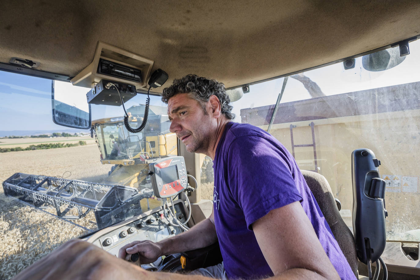 El agricultor, al volante de su tractor, revisa el trabajo de la cosechadora.