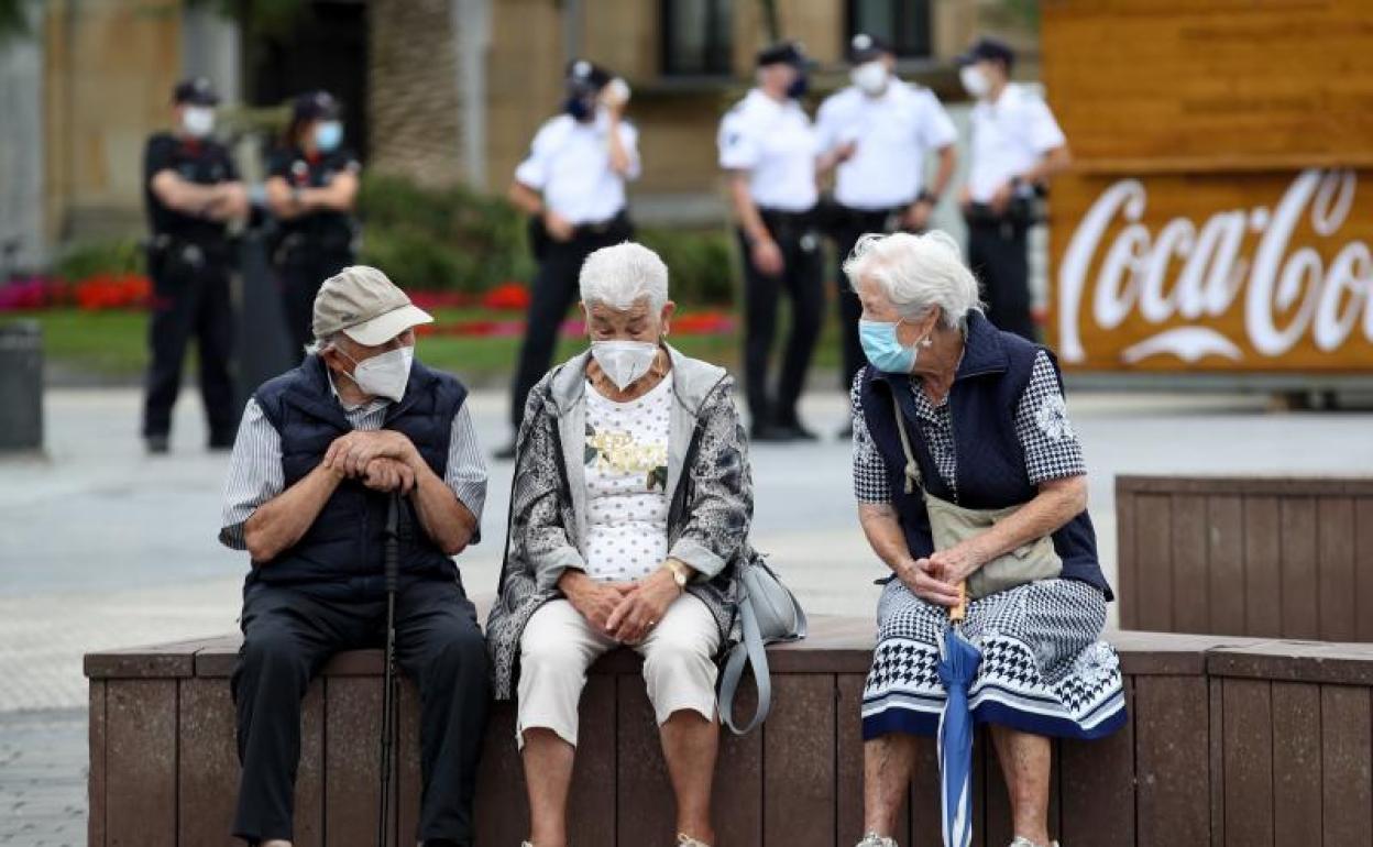 Unos ancianos conversan protegidos con mascarillas. 