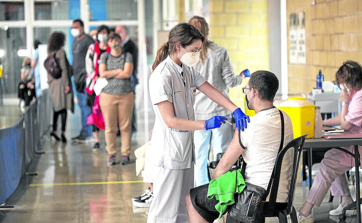 Una sanitaria de Osakidetza vacuna a un joven en uno de los centros habilitados para la campaña de inmunización. 