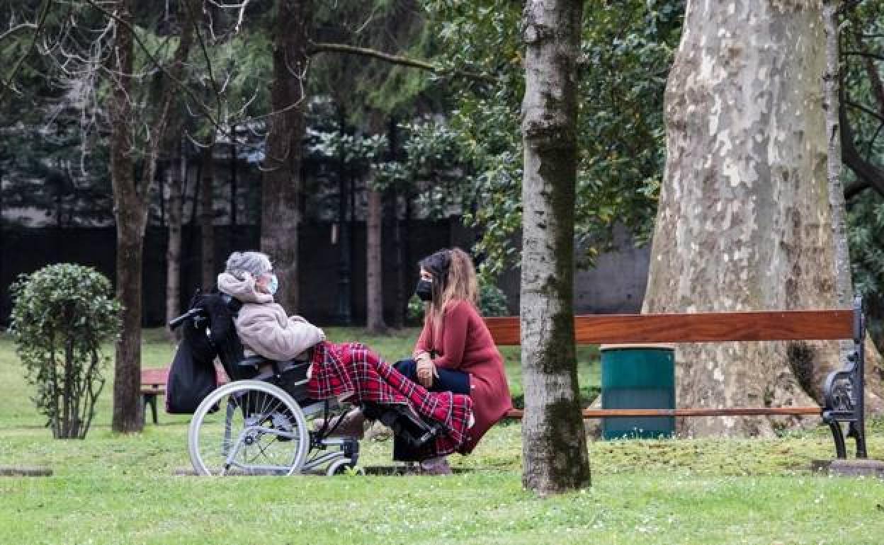 Una mujer acompaña a una persona mayor en los jardines en La Misericordia. 