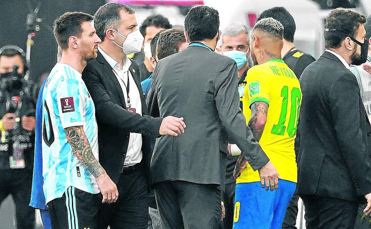 Messi y Neymar charlan con responsables de ambos equipos tras suspenderse el encuentro. 