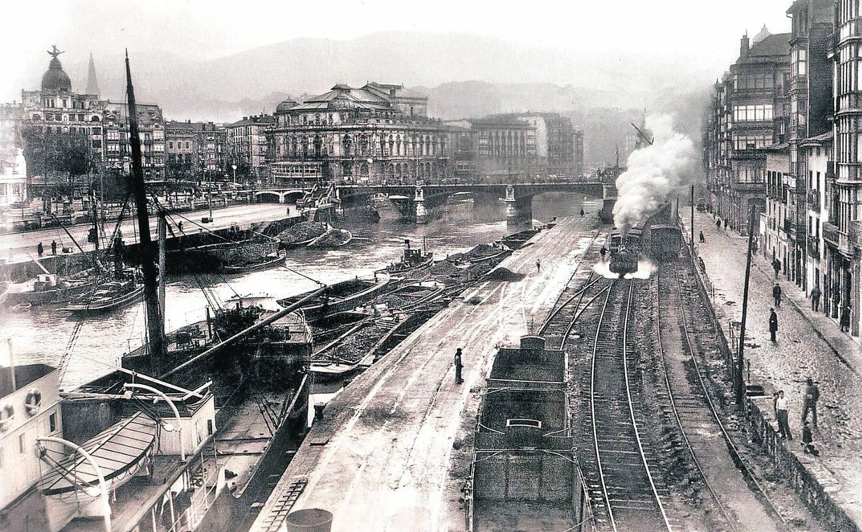 Vista del Muelle de Ripa en el año 1931 con barcos cargando carbón y la línea de ferrocarril; al fondo, el puente de El Arenal y el Teatro Arriaga. 