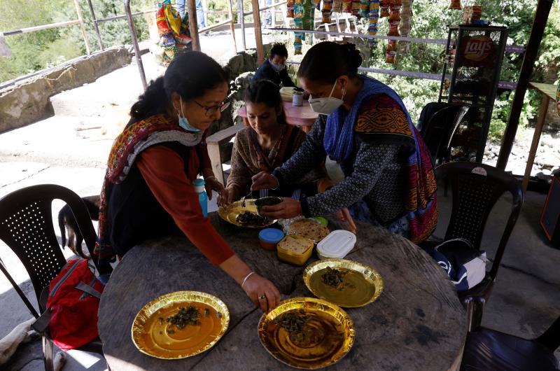 Los trabajadores de la salud comen su almuerzo mientras toman un descanso de su caminata para ir a vacunar a los pueblos remotos del Himalaya.