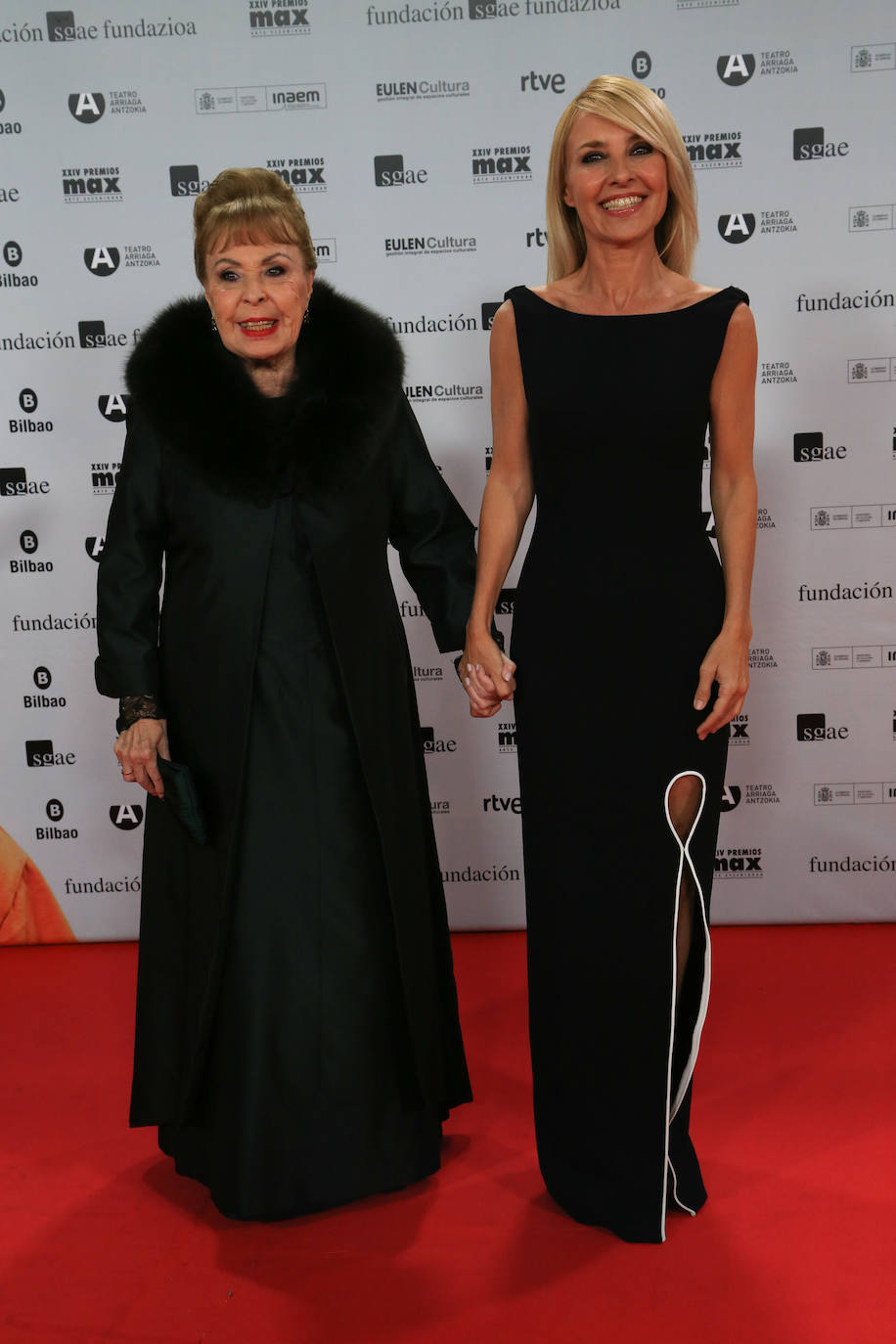 La actriz Cayetana Guillén Cuervo acudió a la gala de los Max con un favorecedor vestido negro con apertura lateral y contraste blanco de la diseñadora guipuzcoana Maitane Campaña. Posó en el photocall junto a su madre, Gemma Cuervo, que recibía el premio de honor y que lució un vestido largo verde oscuro y un abrigo en el mismo color. 