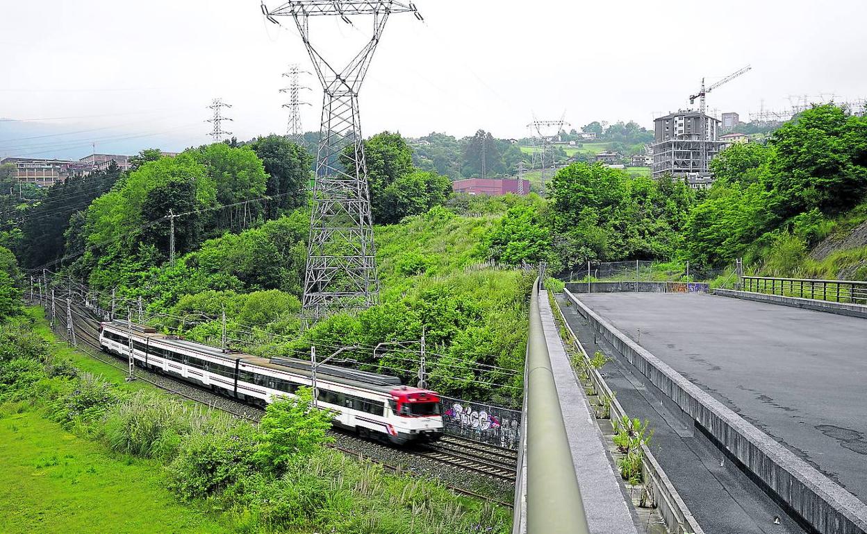 Un tren de Cercanías, de la línea Orduña-Bilbao, pasa por debajo del viaducto ubicado en la frontera entre Basauri, Zaratamo y Arrigorriaga. 