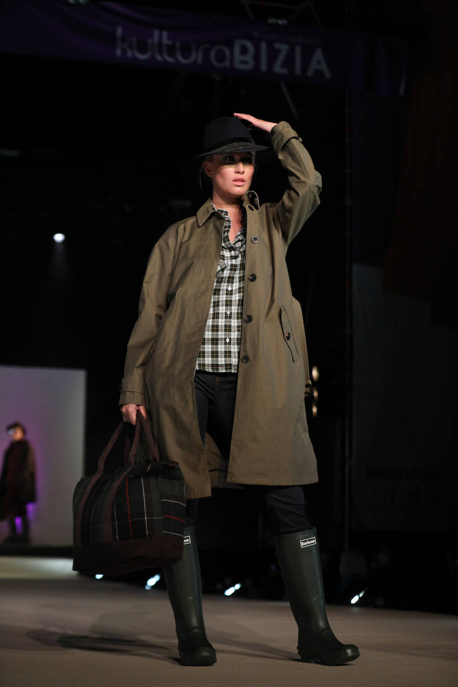 Gabardina combinada con botas de agua y camisa de cuadros.