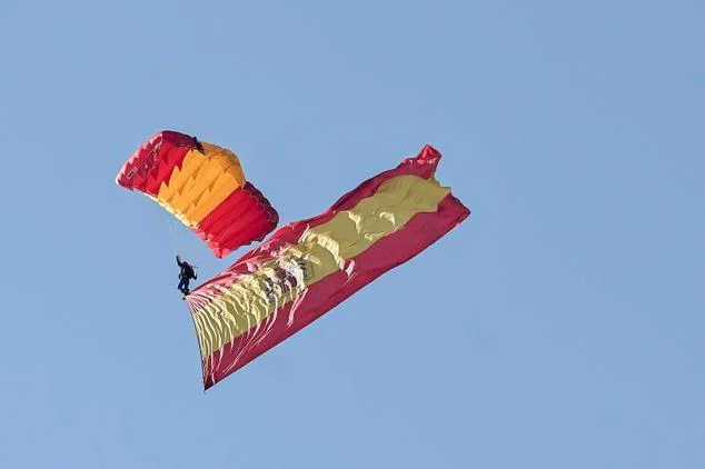 Un paracaidista de la Patrulla Acrobática de Paracaidismo del Ejército del Aire salta sobre la plaza de Lima, en el Paseo de la Castellana.