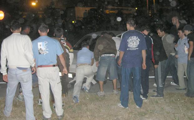 Espectadores devuelven un turismo accidentado a la carretera en una imagen de hace más de quince años.