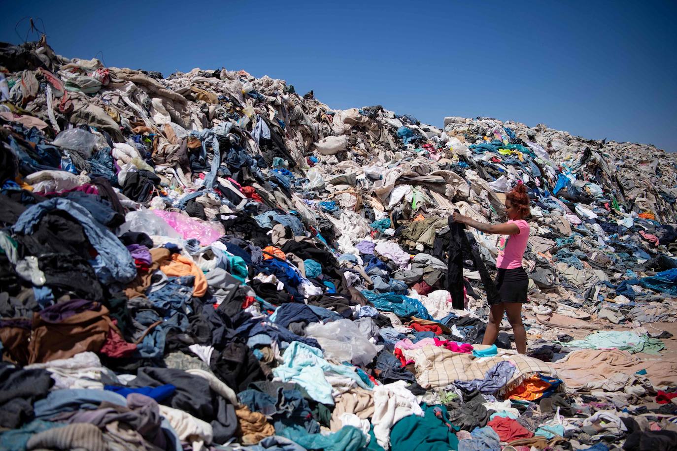 Una mujer escaba entre los residuos de ropa en el desierto de Atcama. 