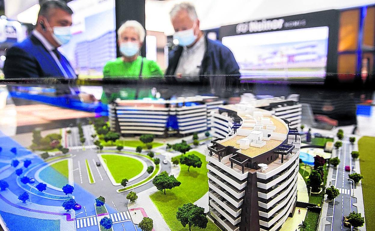 Visitantes de una feria inmobiliaria observan las maquetas de una promoción de viviendas. 