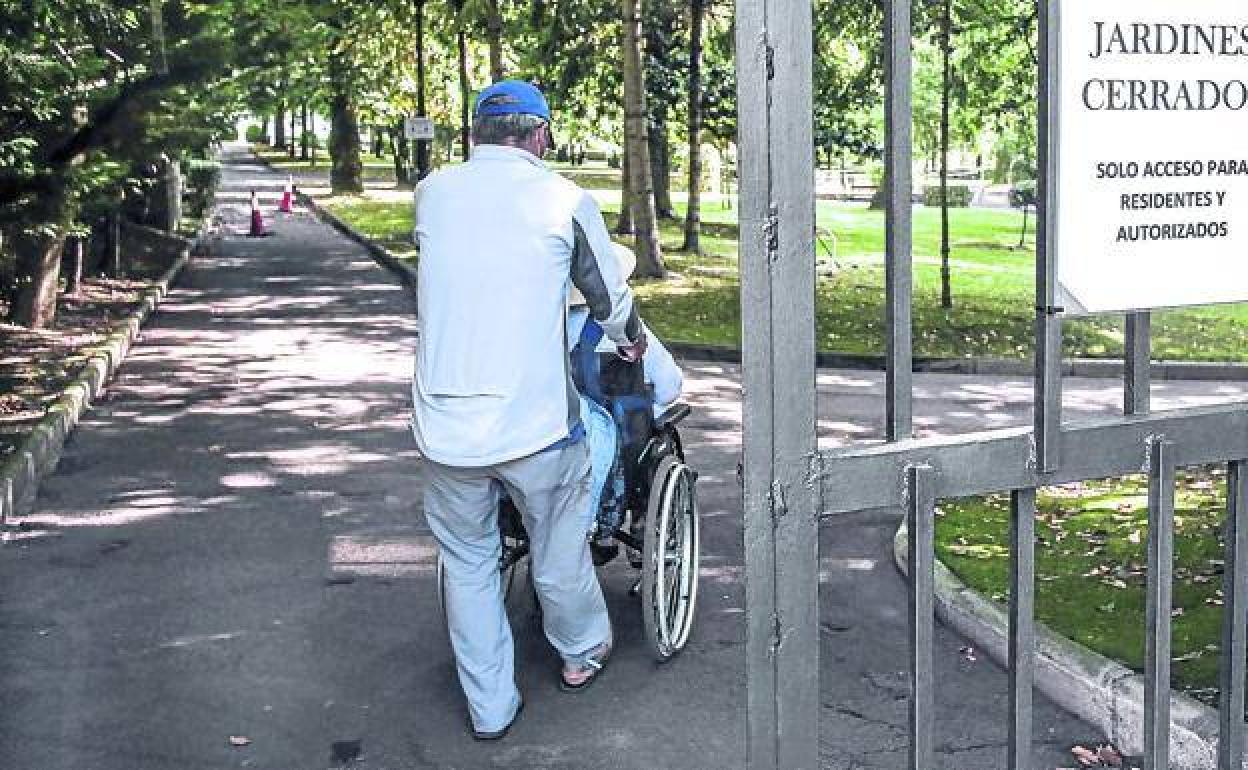 Un familiar acompaña a un dependiente durante una visita por los jardines de La Misericordia.