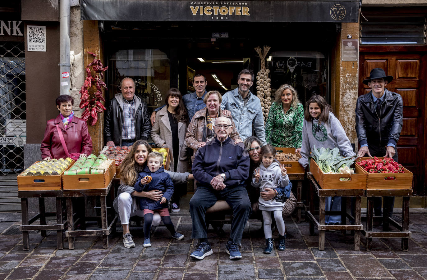 Retrato familiar delante del negocio. En la fila de atrás, de izquierda a derecha, María Antonia Rey, Bittor Madariaga, Naomi Couso, Igor Madariaga, Soledad Rey, Sergio Fernández, Beatriz Fernández, Andrea Sáez del Burgo e Iñigo Sáez del Burgo. Delante, en el mismo sentido, Luz Verástegui, Lucas Fernández, Víctor Fernández Amatriain, Estíbaliz Fernández y Donna Sáez del Burgo.