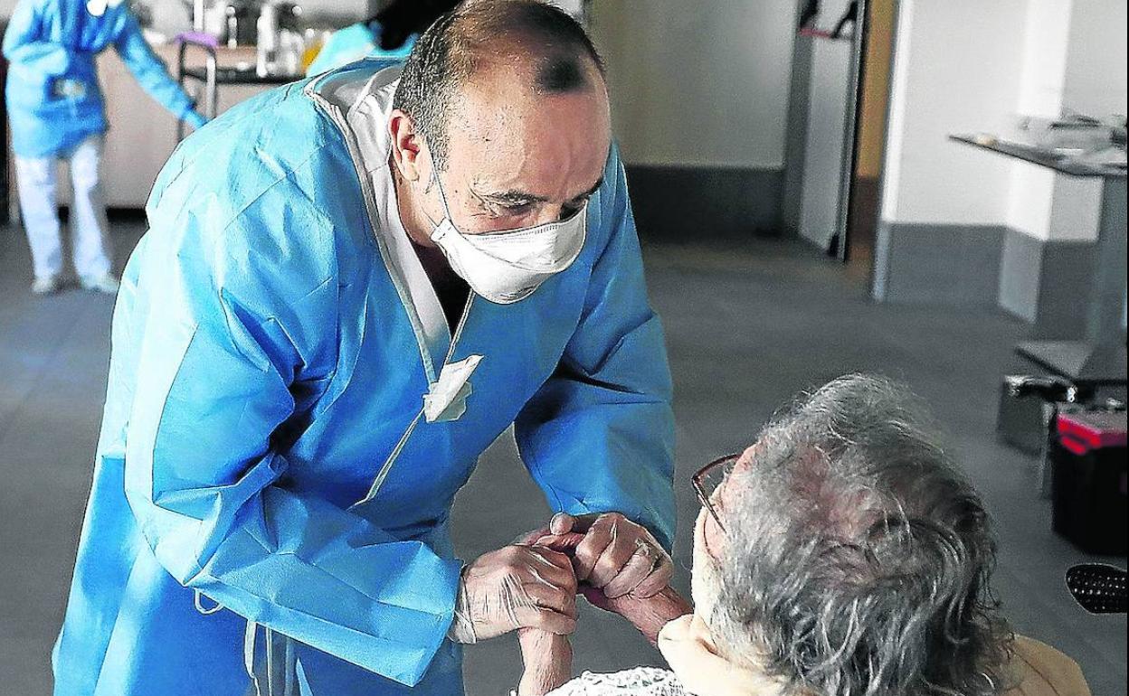 Un trabajador sociosanitario atiende a una usuaria de una residencia.