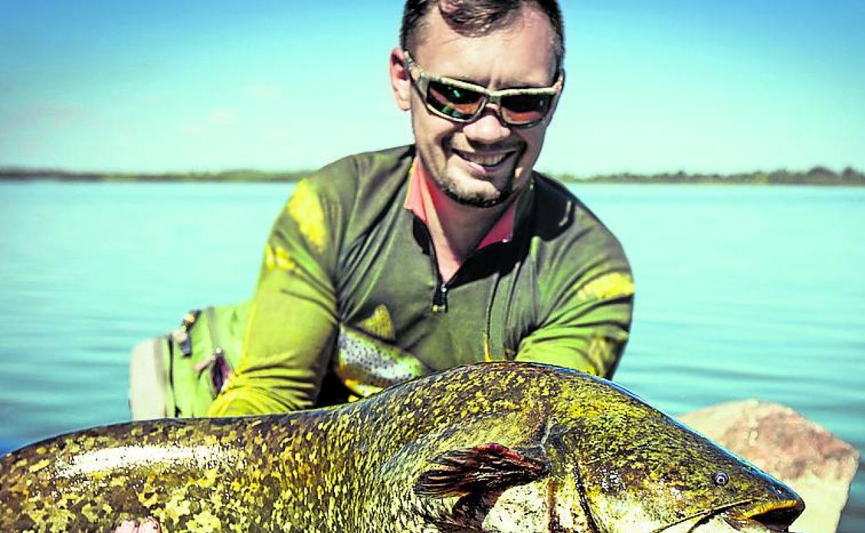 Un pescador exhibe un siluro. 