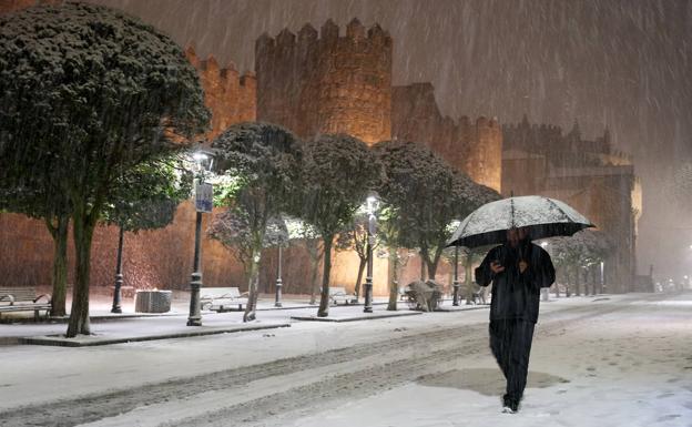 Un hombre camina bajo la nieve por las calles de Avila.